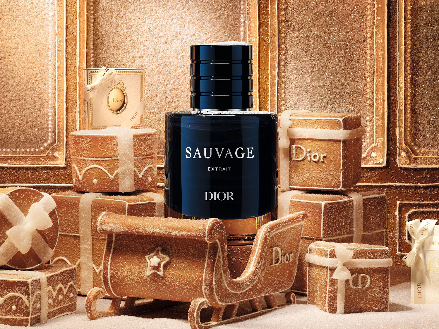 Le parfum Dior Sauvage Extrait, présenté dans un flacon bleu foncé avec des accents dorés, est entouré de cadeaux de Noël en pain d'épices et d'un traîneau, le tout saupoudré de sucre, créant une ambiance festive et luxueuse.