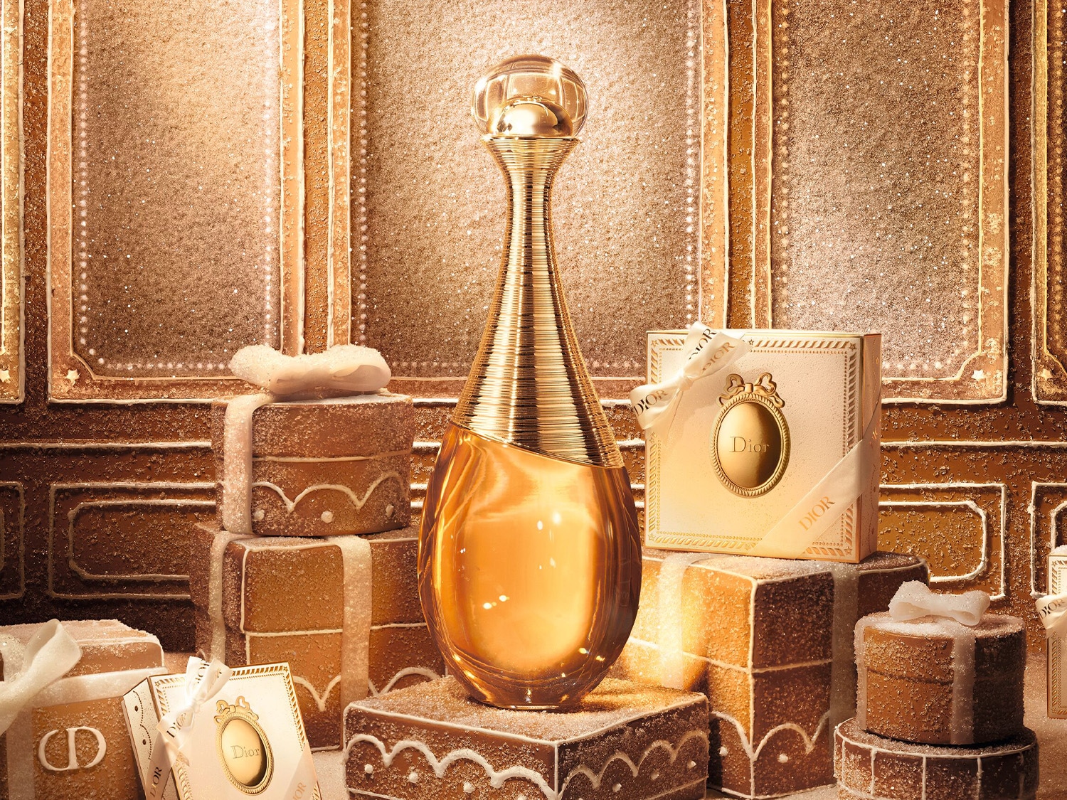 Le parfum J'adore de Dior, dans son flacon doré emblématique, est présenté au centre d'une scène festive, entouré de coffrets cadeaux et de décorations scintillantes.