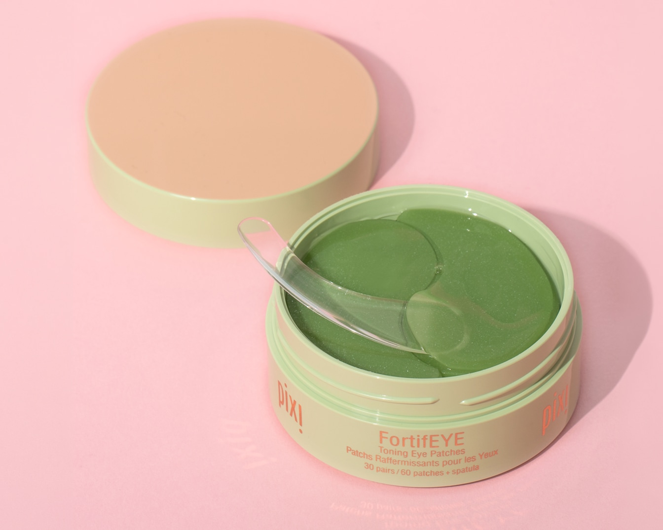 Ontdek de Pixi FortifEYE oogpatches in een pastelgroene pot met transparante spatel op een zachtroze achtergrond voor een frisse oogopslag.