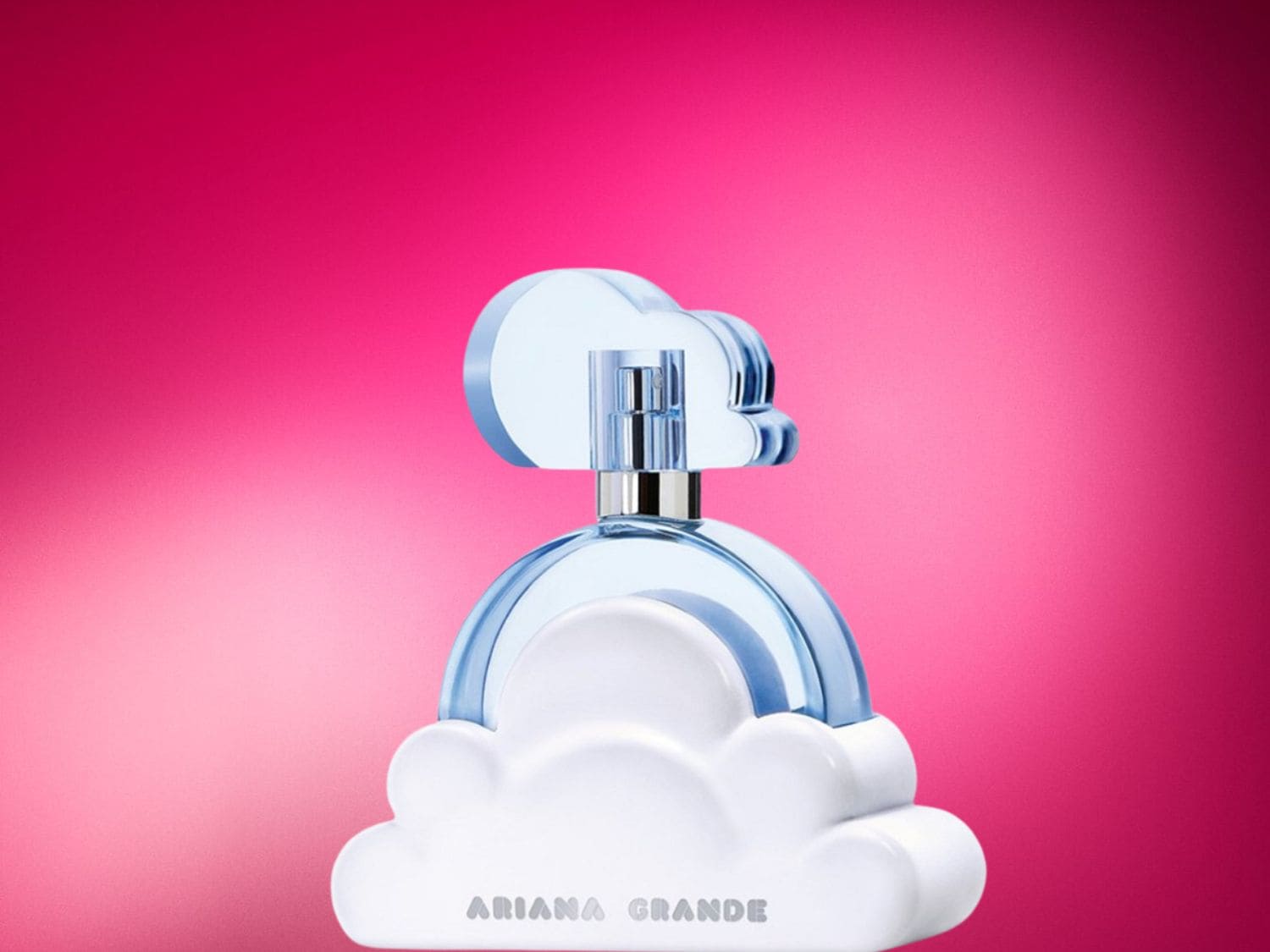 Parfém Ariana Grande Cloud v modré lahvičce ve tvaru mraku s bílým podstavcem a stříbrným rozprašovačem, na růžovém pozadí.