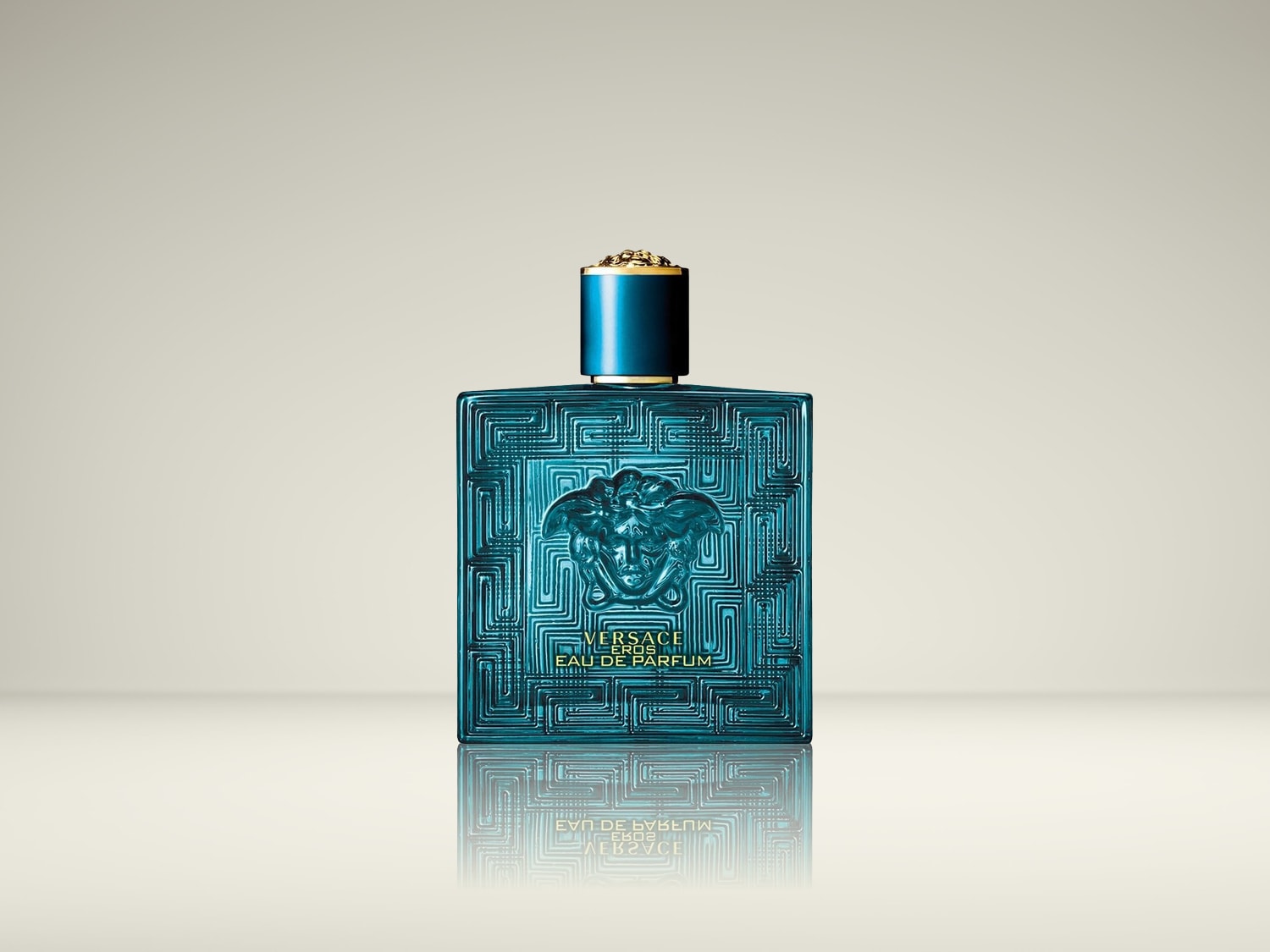 De Versace Eros Eau de Parfum is een turquoise, vierkante fles met een gouden dop en een reliëf van het Medusa-hoofd, staand op een reflecterend oppervlak.
