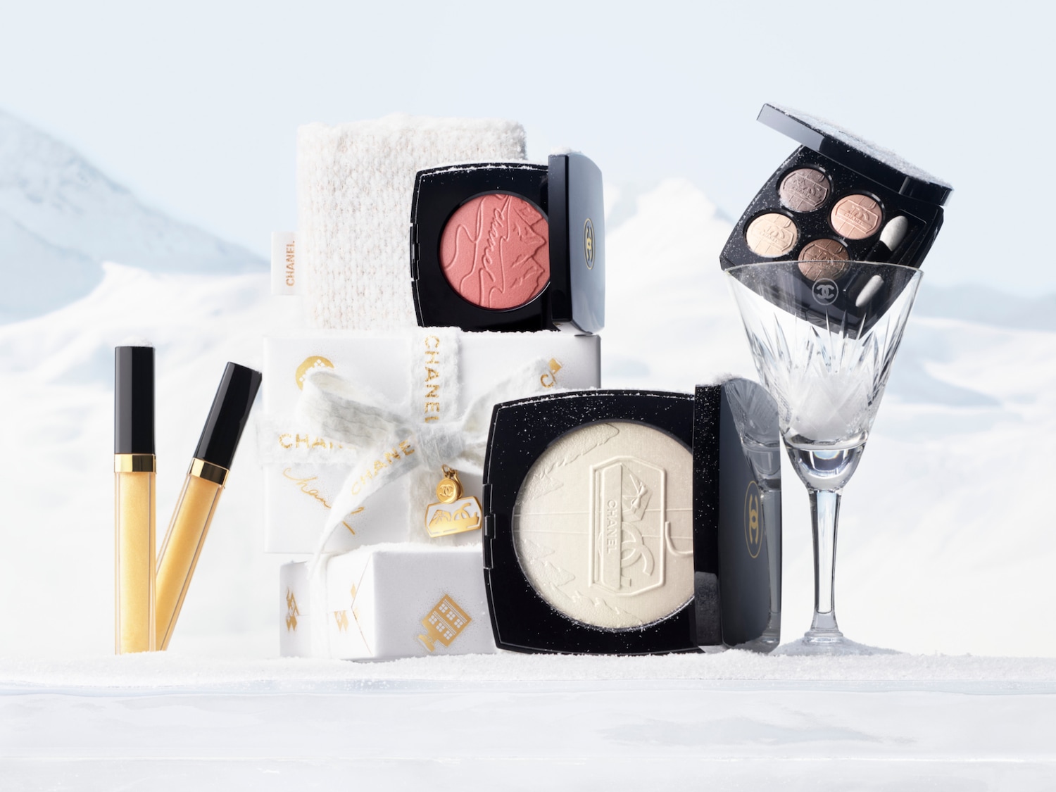 Een luxe collectie Chanel make-producten, waaronder lipgloss, blush en een oogschaduwpalet, prachtig gepresenteerd in een winterse sneeuwlandschap.