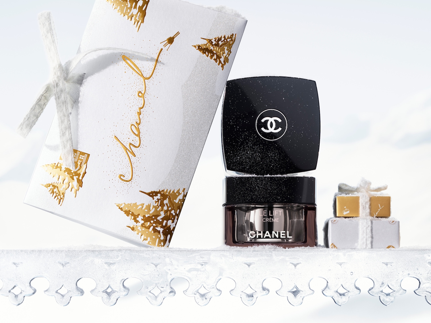 Ontdek de Chanel Le Lift Crème in een feestelijke verpakking op een besneeuwde ondergrond, vergezeld van mini cadeautjes.