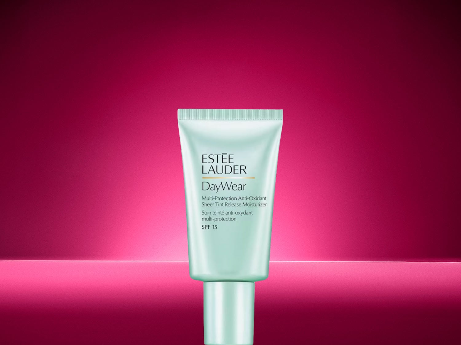 Die zartgrüne Tube der Estée Lauder DayWear Feuchtigkeitscreme mit LSF 15 präsentiert sich vor einem kräftigen pinken Hintergrund und schützt die Haut optimal vor schädlichen Umwelteinflüssen. Jetzt entdecken und strahlenden Teint sichern!
