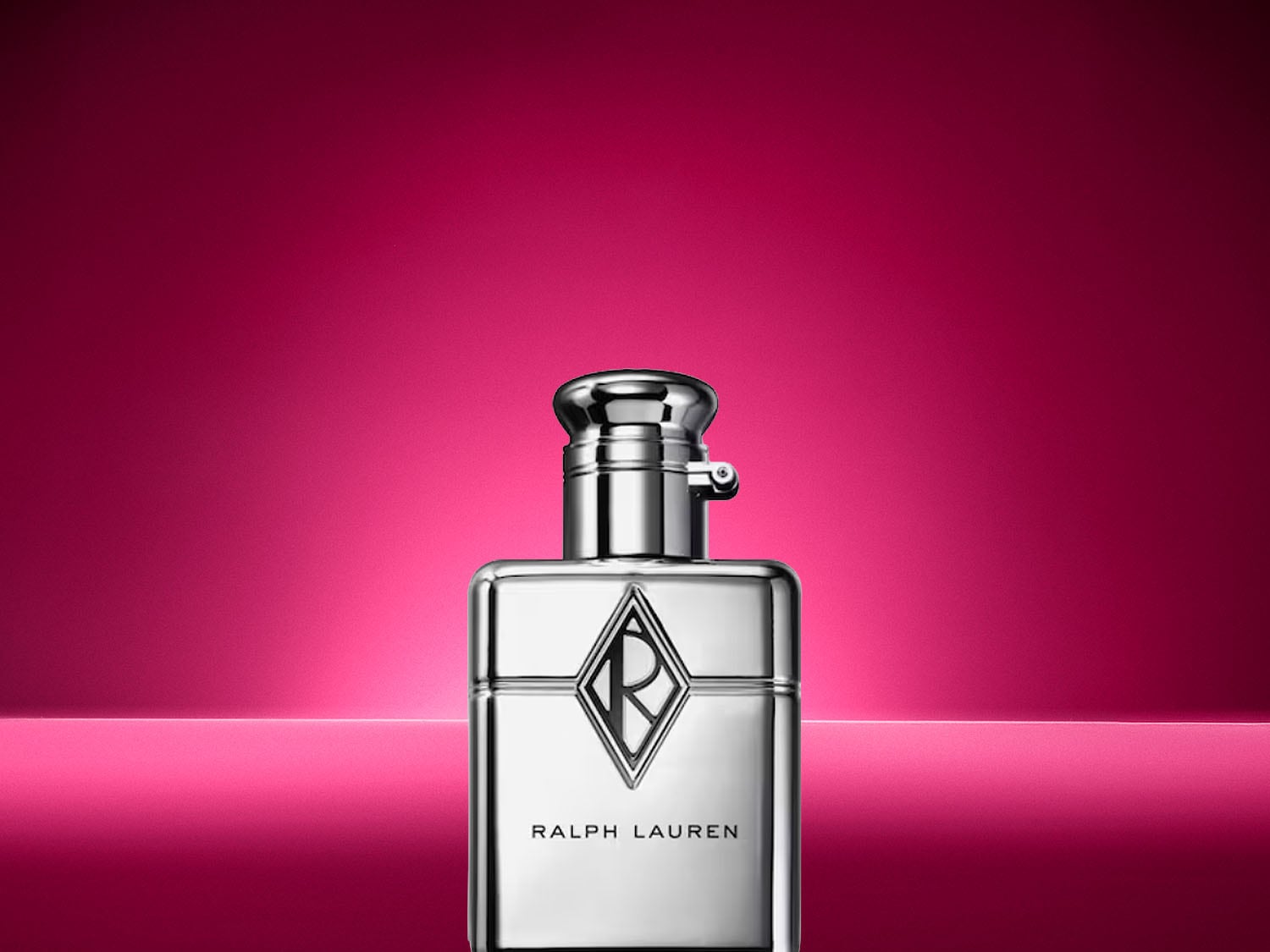 Ein glänzender, silberner Ralph Lauren Parfumflakon mit markantem R-Logo steht vor einem leuchtend pinken Hintergrund. Jetzt entdecken!