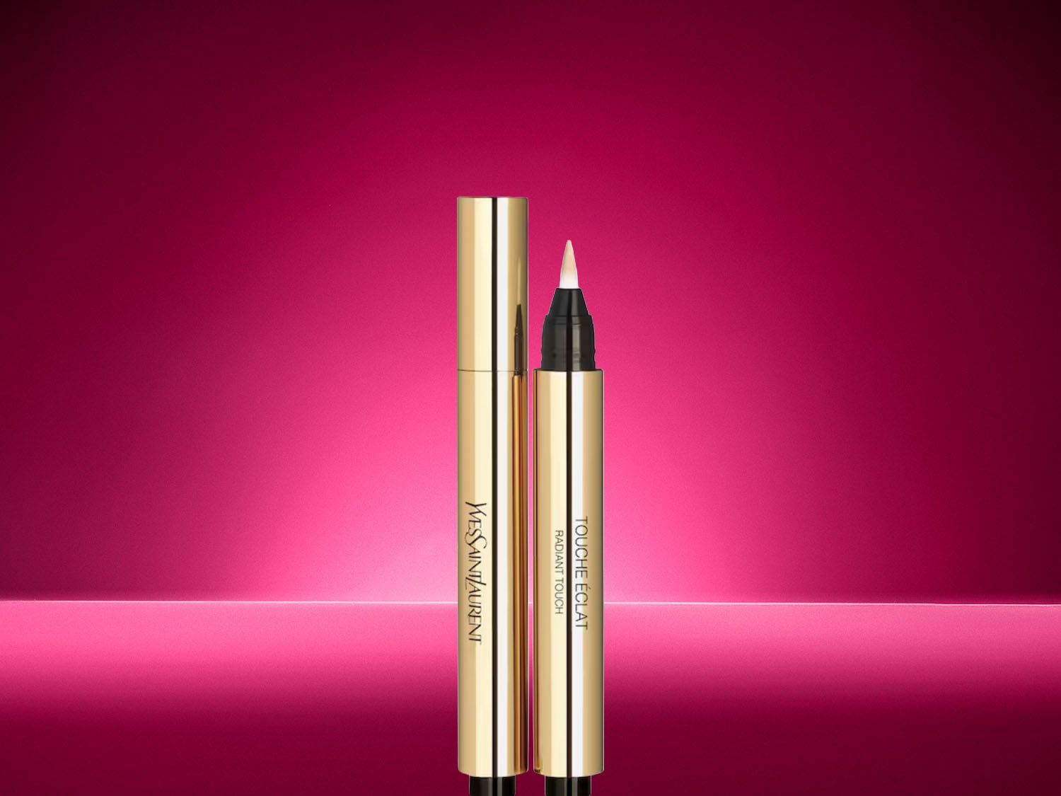 Der goldene Yves Saint Laurent Touche Éclat Concealer-Stift mit feiner Pinselspitze präsentiert sich vor einem leuchtenden, pinken Hintergrund.