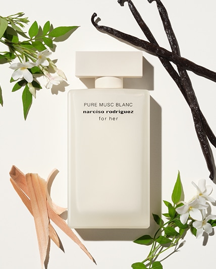 Der rechteckige for her PURE MUSC BLANC Flakon in mattem Weiß liegt auf weißem Hintergrund, umgeben von den Hauptinhatsstoffen des Duftes: Jasmin, Vanille und Zedernholz. 