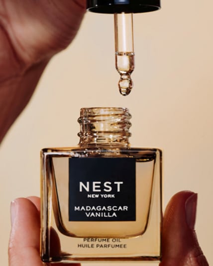 Nahaufnahme eines NEST Madagascar Vanilla Parfümöls: Eine Pipette hält einen Tropfen über dem geöffneten Fläschchen in warmem Licht.