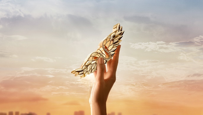 Eine Hand hält das Zadig L'intense in den Himmel mit Wolken und einer Stadt im Hintergrund.