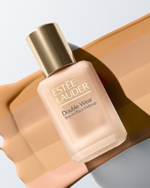Butelka Double Wear Stay-In-Place Makeup SPF 10 ułożona na tle różnych odcieni podkładu.